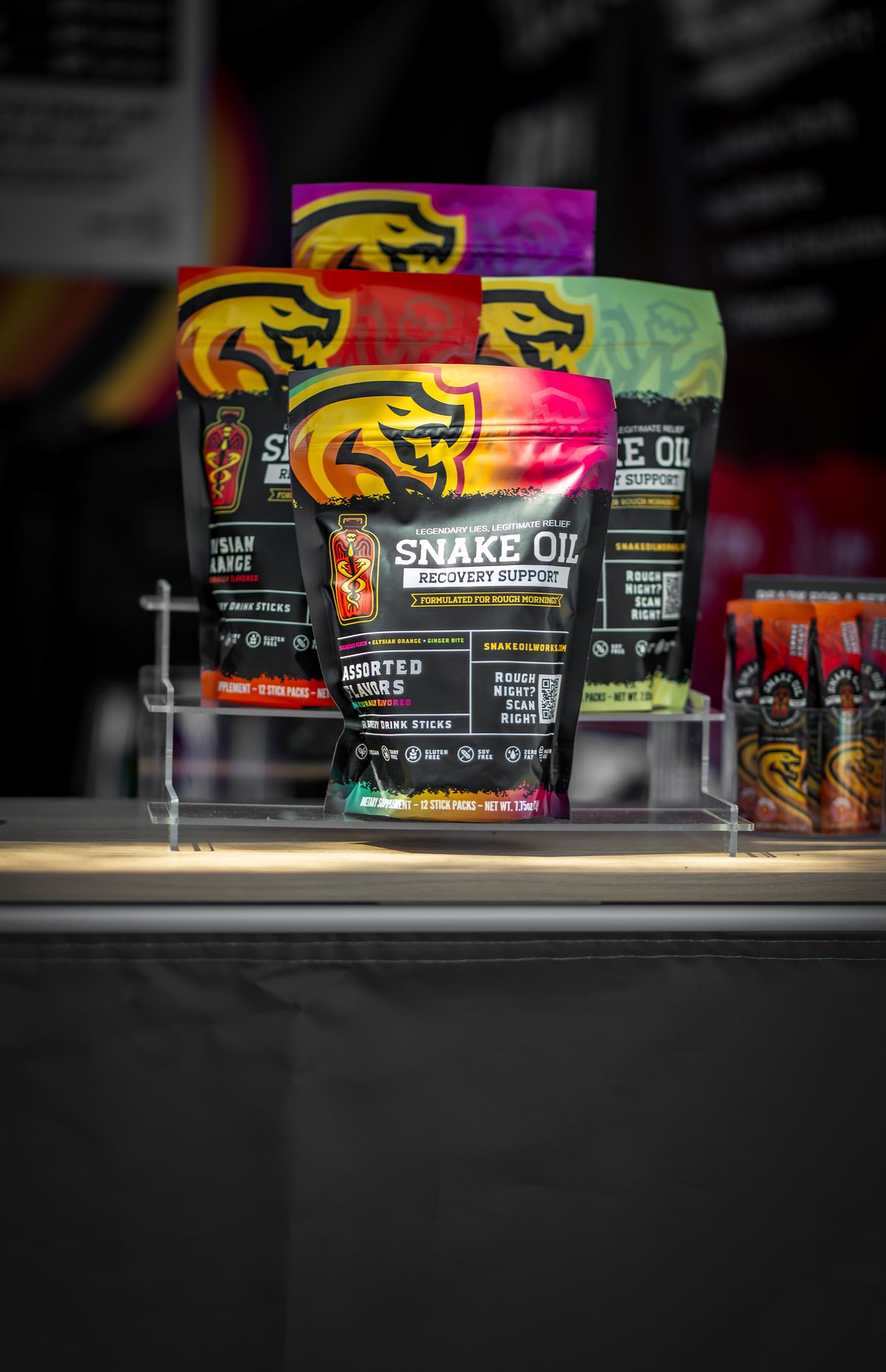 All four Snake Oil pouches on display — Salacious Punch, Elysian Orange, Ginger Bite, and Assorted Varieties