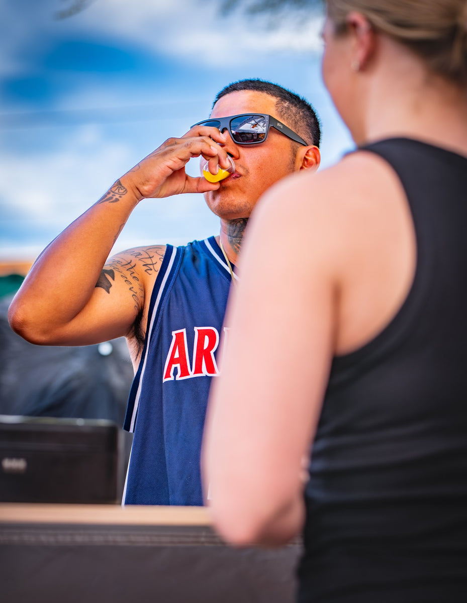 A customer drinking a sample shot of Snake Oil outdoors