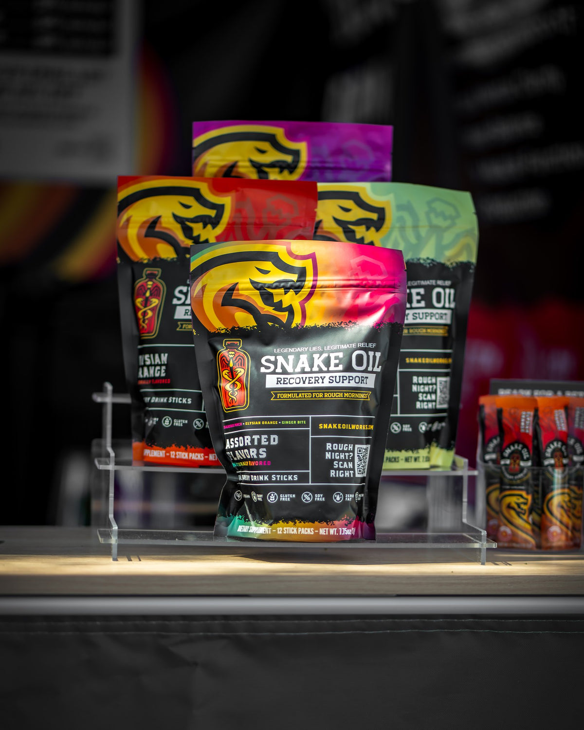 Snake Oil pouches on a retail display riser &mdash; four flavors with single-serve stick packs